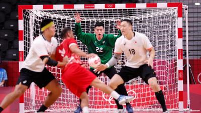 Handball athletes try to score on goalie.